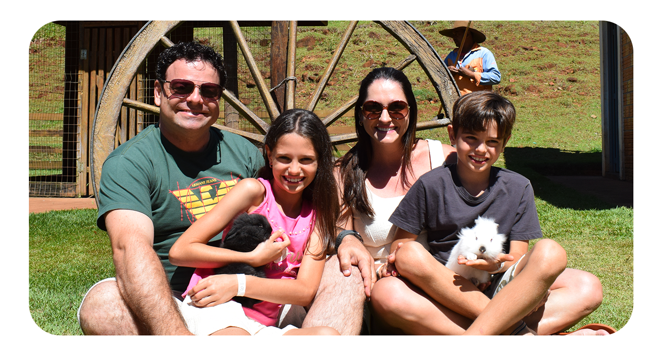 foto de uma familia homem e mulher e dois filhos sentados na grama sorrindo